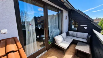 Gemütlicher Balkon mit Sitzgelegenheiten und Blick auf die Nachbarschaft unter blauem Himmel.