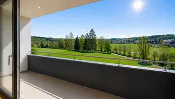 Sonniger Balkon mit weitem Blick über grüne Felder und Bäume, ideal zum Entspannen und Genießen der Natur.