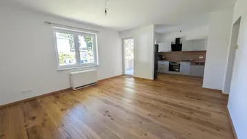 Helles Wohn-Esszimmer mit modernem Parkettboden und Zugang zu einem Außenbereich.
