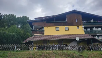Traditionelles Gebäude im Chalet-Stil mit gelber Fassade, Holzelementen und mehreren Balkonen.