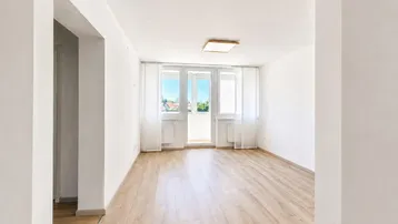 Helles, leeres Zimmer mit modernem Laminatboden und Zugang zu einem Balkon, ideal als Wohn- oder Schlafzimmer.