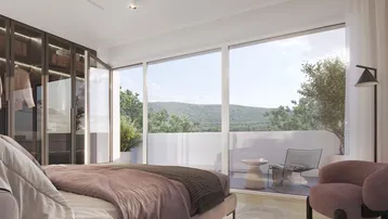 Schlafzimmer mit großen Fenstern, Holzboden, Einbauschrank und Zugang zu einer Terrasse mit Bergblick.