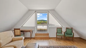 Lichtdurchfluteter Wohnbereich mit Zugang zum Balkon und einem weiten Blick auf die umliegende Landschaft und Berge.