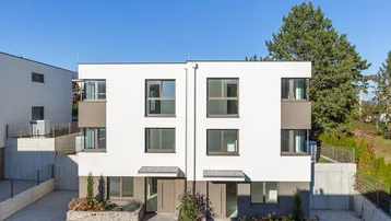 Moderne Doppelhaushälfte mit weißer Fassade und grauen Akzenten unter klarem blauem Himmel.