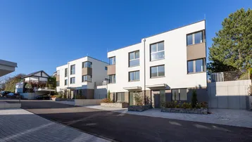 Moderne Reihenhäuser mit klaren Linien und großen Fenstern unter blauem Himmel.