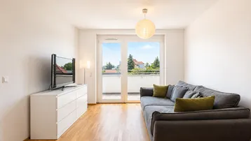 Helles Wohnzimmer mit Parkettboden, großem Sofa und direktem Zugang zum sonnigen Balkon.