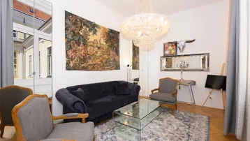 Helles Wohnzimmer mit eleganten Möbeln, Kronleuchter und Parkettboden in einem Altbau.