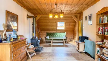 Gemütliches Wohnzimmer im Dachgeschoss mit Holzbalken, Holzofen und rustikalen Möbeln.