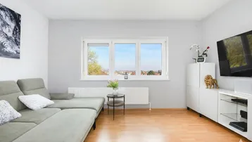 Gemütliches Wohnzimmer mit Ecksofa, Holzboden und weitem Blick über die Landschaft.