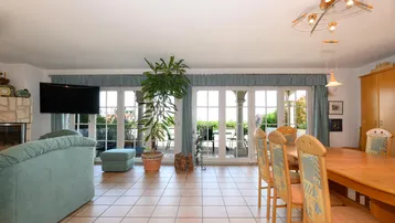 Geräumiger Wohn-Essbereich mit Fliesenboden, Kamin und Zugang zur Terrasse.