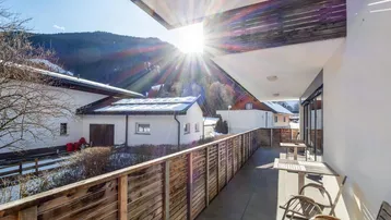 Sonniger Balkon mit Bergblick, Sitzgelegenheiten und viel natürlichem Licht.