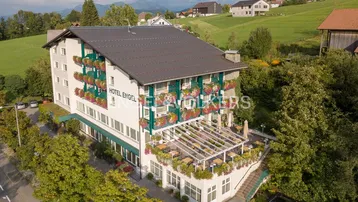 Luftaufnahme des Hotels Engel mit blühenden Balkonen und umliegender grüner Landschaft.