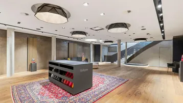 Großzügiger Verkaufsraum mit Holzboden, einem großen Orientteppich und modernen Präsentationsmöbeln.