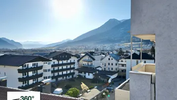 Panoramablick über die Stadt mit umliegenden Bergen und sonnigem Himmel.