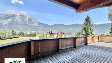 Geräumige Holzterrasse mit atemberaubendem Bergblick und viel Platz zum Entspannen im Freien.