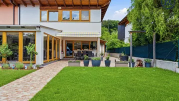 Geräumiger Garten mit gepflegtem Rasen und einer einladenden Terrasse am Haus.