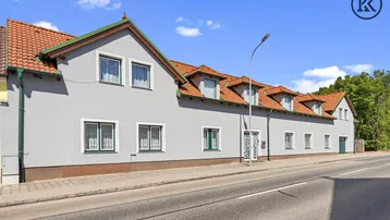 Langes Wohngebäude mit mehreren Gauben, Ziegeldach und direkter Straßenanbindung.