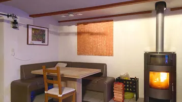 Gemütlicher Essbereich mit einem modernen Holzofen, Fliesenboden und einer Eckbank für gesellige Runden.