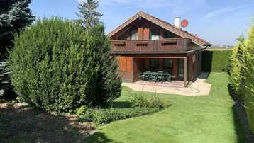 Charmantes Holzhaus mit gepflegtem Garten und überdachter Terrasse im Grünen.