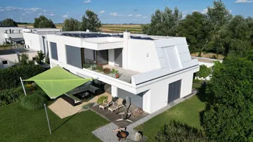Modernes Einfamilienhaus mit großem Garten, Sonnenterrasse und Photovoltaikanlage auf dem Dach.
