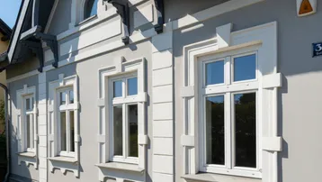 Historische Fassade eines Gebäudes mit verzierten Fensterrahmen und klassischer Architektur.