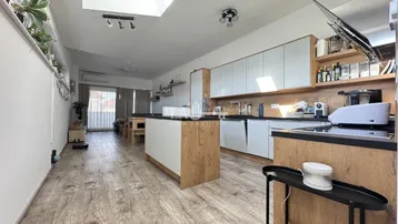 Moderne offene Küche mit Holz- und weißen Elementen, ausgestattet mit einer Kücheninsel und Dachfenster.