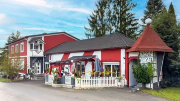 Auffälliges Gebäude mit rot-weiß gestreifter Fassade und überdachter Terrasse mit Sitzgelegenheiten.