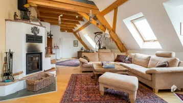Gemütliches Wohnzimmer im Dachgeschoss mit Kamin, Holzbalken und schrägen Decken.