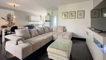 Geräumiger offener Wohnbereich mit beigem Ecksofa, modernem TV-Möbel und Blick auf den Essbereich.