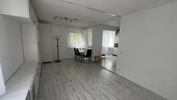Heller Wohn- und Essbereich mit weißer Schrankwand, Esstisch und Blick in den angrenzenden Küchenbereich.