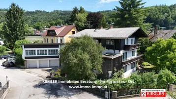 Luftaufnahme des Anwesens mit mehreren Gebäuden, umgeben von viel Grün und einer Straße.