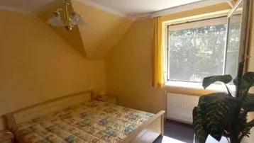 Gemütliches Schlafzimmer mit Dachschräge, Teppichboden und Fenster für natürliches Licht.