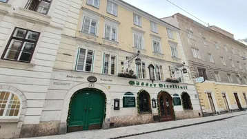 Historisches Geb äude mit traditioneller Fassade, grünen Türen und Kopfsteinpflasterstraße in einer Gasse.