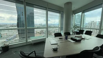 Moderner Konferenzraum in einem Hochhaus mit großen Fenstern und Panoramablick auf die Stadt.