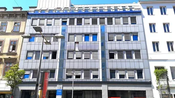 Modernes Bürogebäude mit blauen Akzenten und vielen Fenstern in städtischer Umgebung.