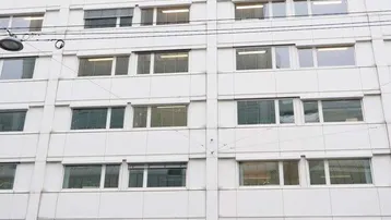 Die Fassade eines modernen Bürogebäudes mit vielen Fenstern und einem Geschäft im Erdgeschoss.