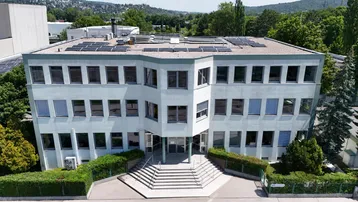 Modernes Bürogebäude mit mehreren Etagen, großen Fenstern und Photovoltaikanlage auf dem Dach.