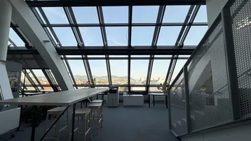 Geräumiges Büro mit schrägen Glasfenstern, hohen Decken und weitem Blick über die Stadt.