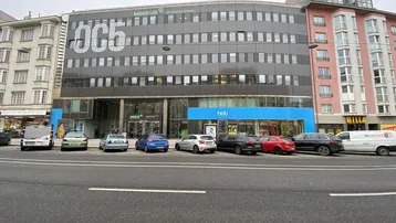 Modernes Geschäftsgebäude mit dunkler Fassade und großen Fenstern an einer belebten Straße.