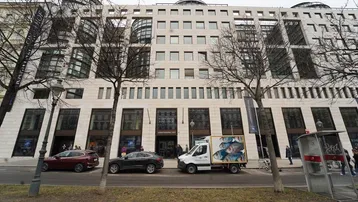 Moderne Geschäftsfassade eines großen Gebäudes mit vielen Fenstern und Geschäften im Erdgeschoss.