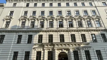 Die Fassade des historischen Gebäudes präsentiert sich mit vielen Fenstern und klassischer Architektur.