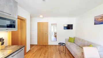 Heller Wohnbereich mit integrierter Küchenzeile, Sofa und Holzboden.