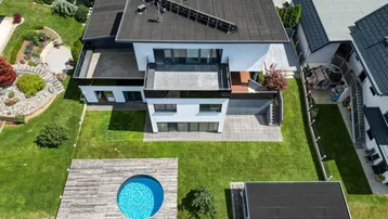 Luftaufnahme eines modernen Hauses mit Garten, Rasenfläche und kleinem runden Pool.
