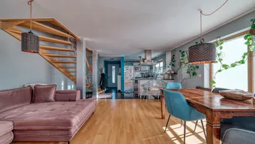 Geräumiger offener Wohn- und Essbereich mit Holzboden und Treppe zum Obergeschoss.