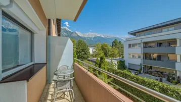 Sonniger Balkon mit Sitzgelegenheiten und beeindruckendem Bergblick.