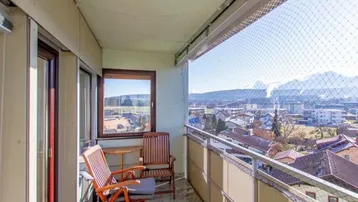 Gemütlicher Balkon mit Holzsitzmöbeln und weitem Blick über die Stadt und Berge.