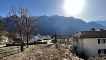 Sonnige Aussicht auf die umliegende Berglandschaft und benachbarte Häuser.