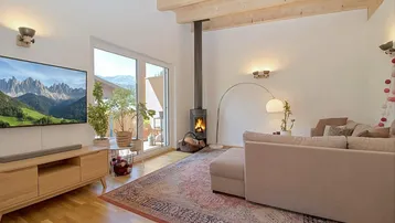 Helles Wohnzimmer mit Kamin, Holzbalkendecke und Zugang zu einem Balkon mit Bergblick.