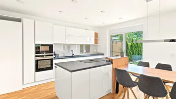 Moderne, offene Küche mit weißen Hochglanzfronten, Kochinsel und direktem Zugang zum Garten.