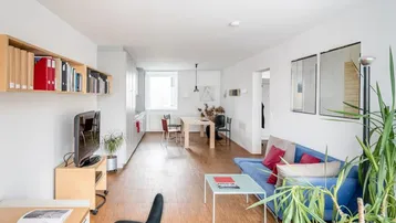 Helles, offenes Wohnzimmer mit integrierter Küche, Essbereich und Parkettboden.